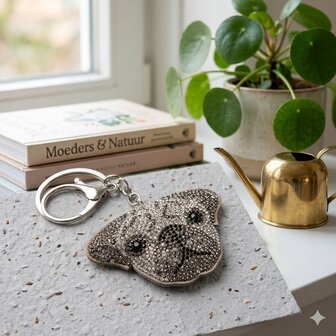 Detailopname van een luxe sleutelhanger in de vorm van een hond met kristallen.
