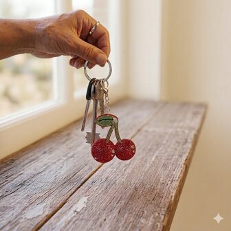 Detailopname van een luxe sleutelhanger in de vorm van kersen met kristallen.