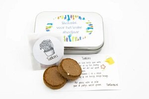 Detailopname van het zadendoosje met tekst en de geopende inhoud met aardtabletten