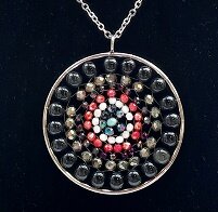 Detailopname van een onyx steen in een zilverkleurige mandala hanger.