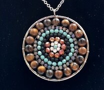 Detailopname van de rvs mandala hanger met goudbruine tijgeroog kralen