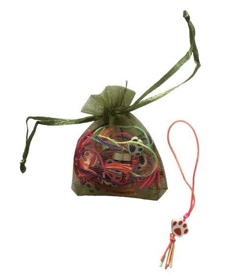 Klein organza zakje gevuld met kleurrijke hondenpoot hangers.