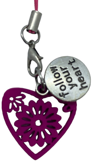 Detailopname van de zilverkleurige hanger met de gegraveerde tekst Follow your heart