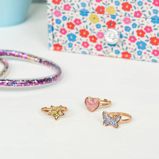 Detail van een goudkleurig ringetje met een hartje en glitters.